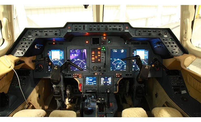 The cockpit of a Hawker jet with multiple display screens and controls.
