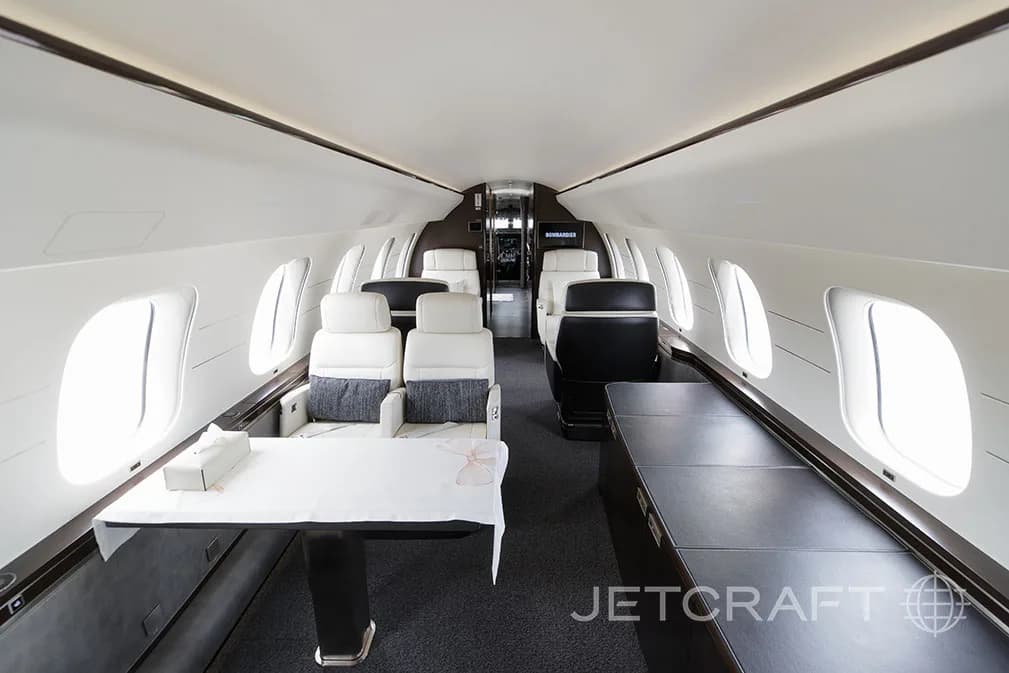 A view of the Bombardier Global 7500 cabin with a table set for dining and multiple white leather seats.