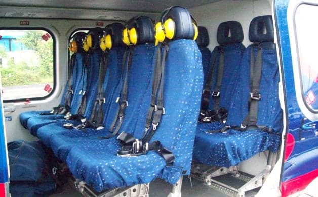 Interior view of the helicopter cabin with blue seats and headsets.
