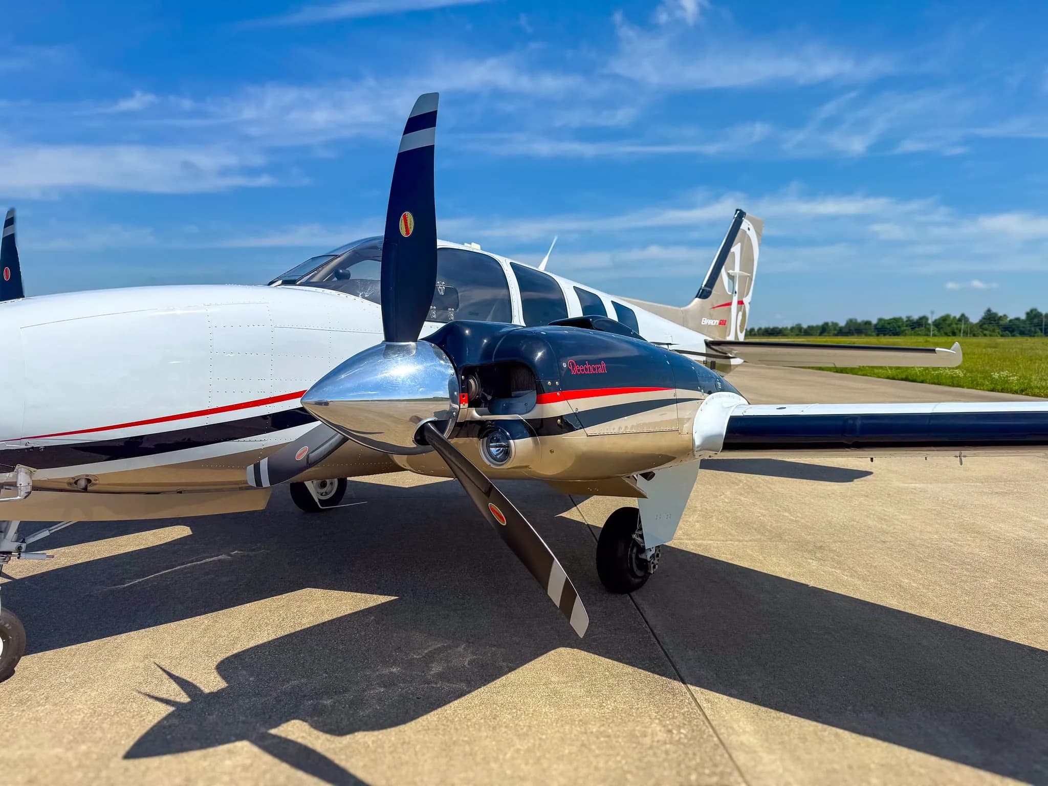 Close-up of the right engine and propeller of a white and gold Beechcraft Baron G58.