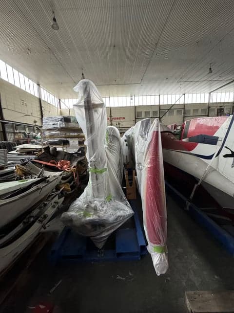 Aircraft parts wrapped in plastic in a hangar.