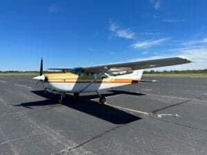 A Cessna 182RG on the tarmac with a white and gold paint scheme.