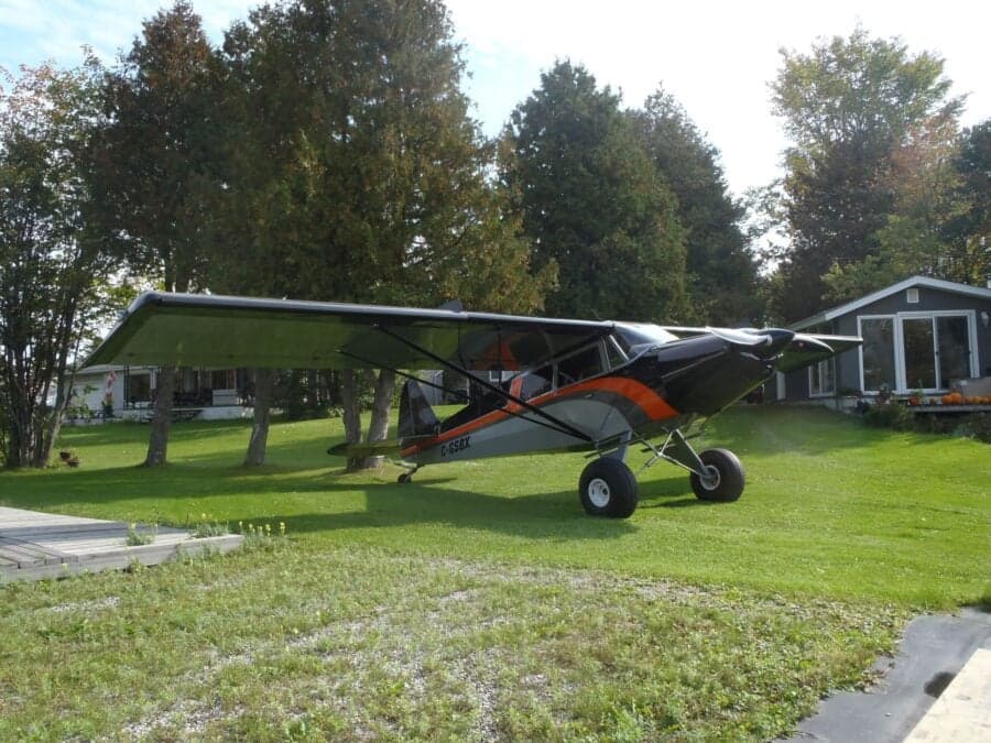 A black, gray, and orange Super Cub is parked on a grassy lawn.