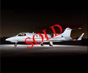 A silver jet aircraft parked on the tarmac at night, marked with a 'SOLD' overlay.
