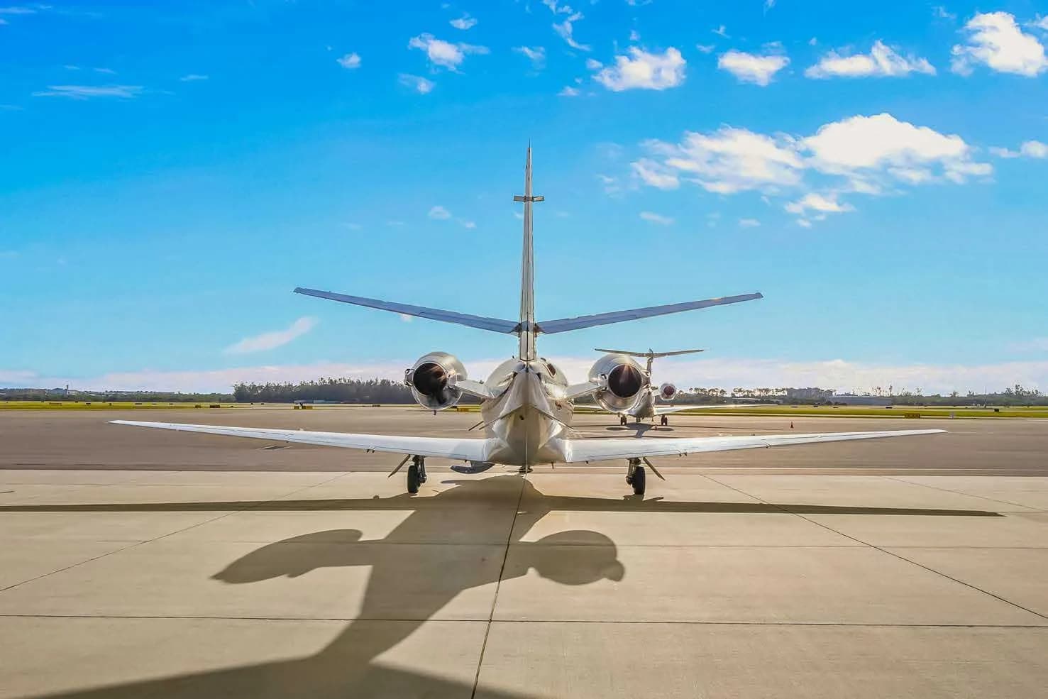 A direct rear view of a white Cessna Citation business jet, N846JS, parked on an airport tarmac under a bright blue sky.