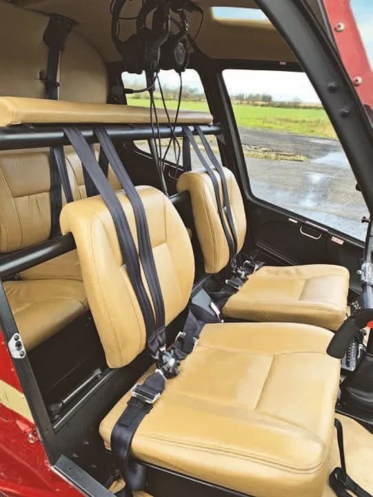 The tan leather seats and interior of a Robinson R66 Turbine helicopter cabin.