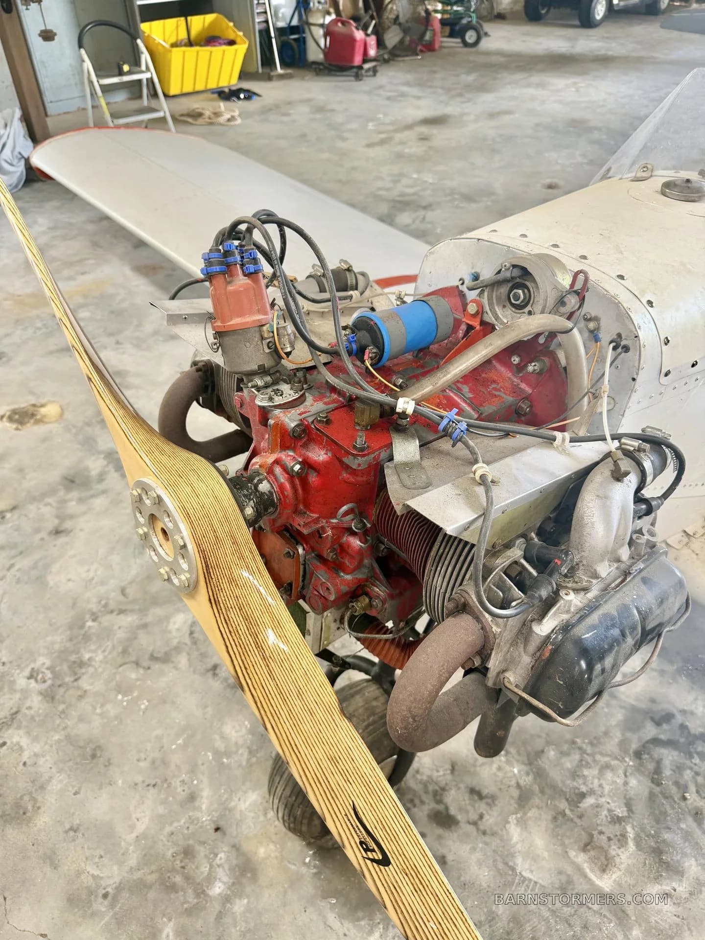 A close-up view of the exposed red engine and wooden propeller of an experimental aircraft.