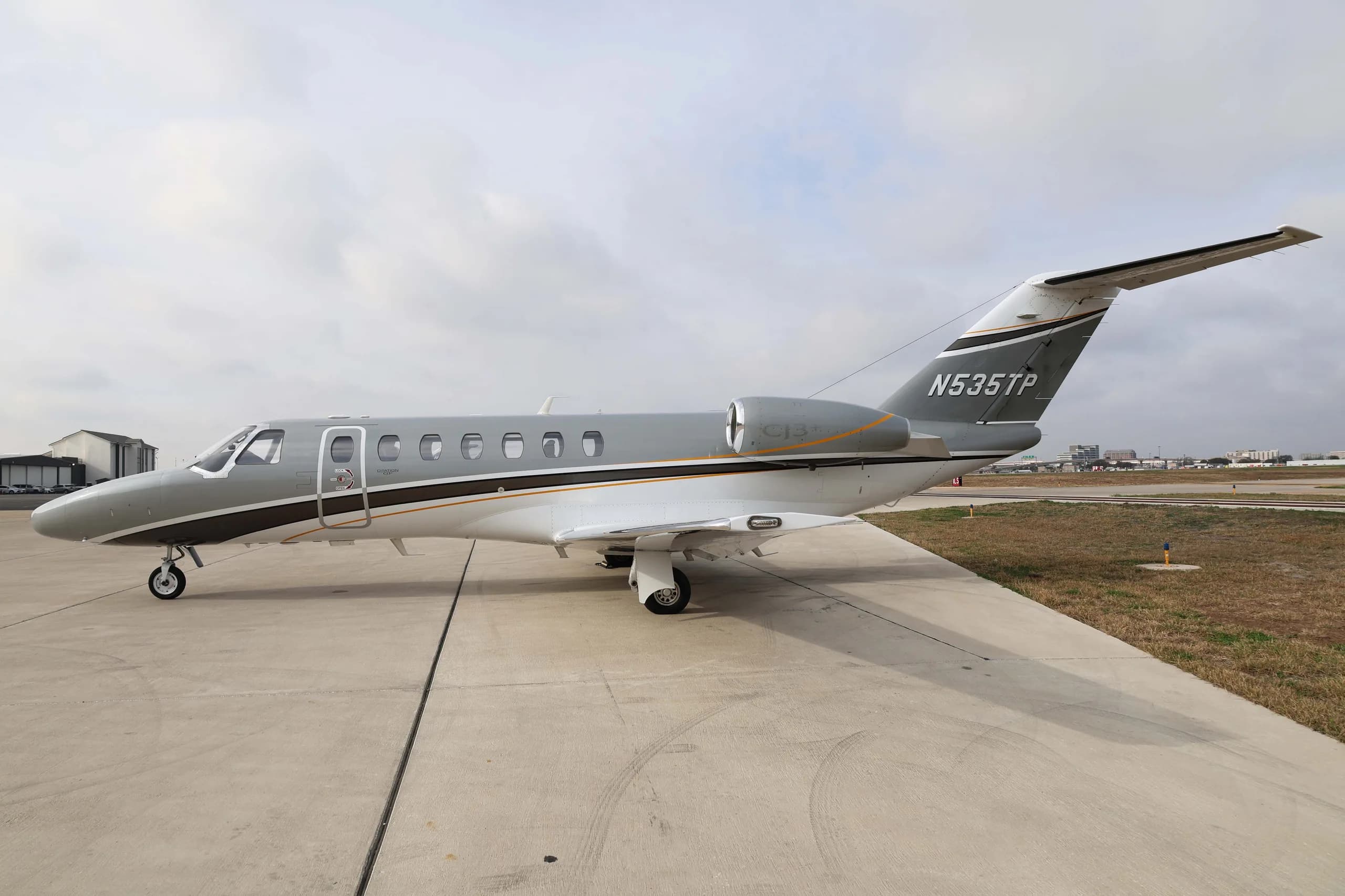 A three-quarter rear view of the Cessna Citation CJ3+ business jet, registration N535TP, with a grey and white paint scheme, parked on an airfield.
