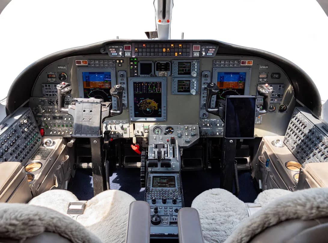 Aircraft cockpit with instrument panel and sheepskin seat covers.