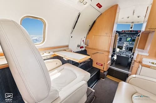 The interior of a Learjet 45XR with white leather seats and a fold-out table.