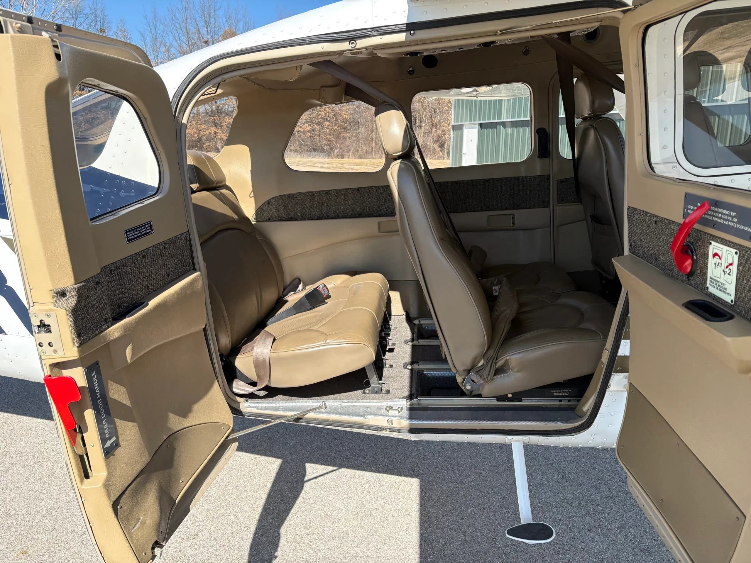 Interior view of the aircraft cabin with tan leather seats and open doors.