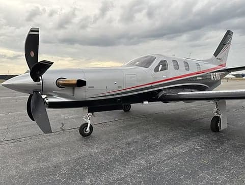 A TBM 930 aircraft with a silver and gray paint scheme is parked on the tarmac.