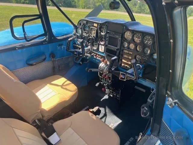 The cockpit and front cabin of a light aircraft show a blue instrument panel and tan pilot seats.