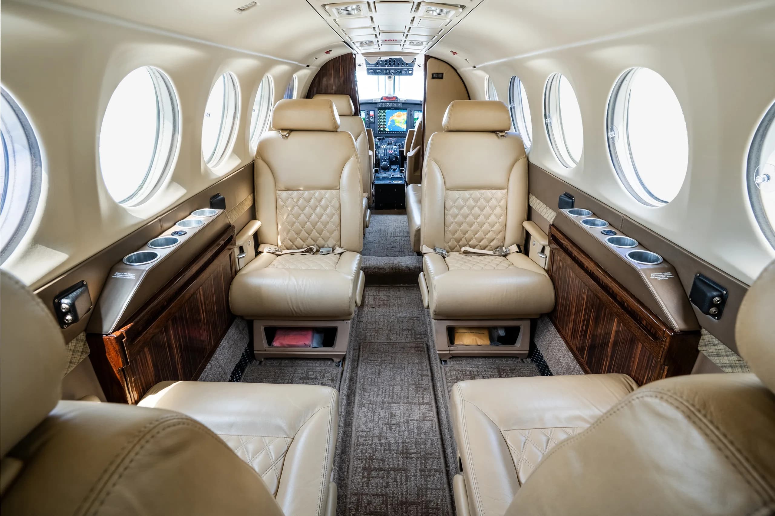 The aircraft cabin interior with beige leather seats and a view towards the cockpit.