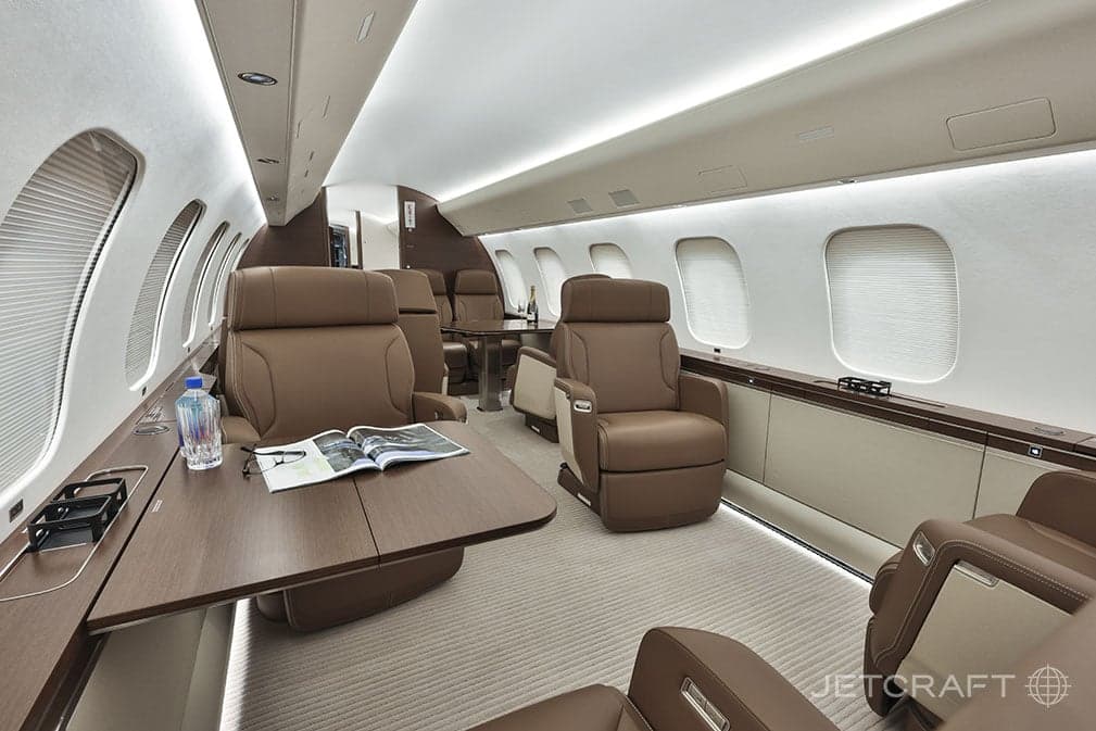 Aircraft cabin with brown leather seats and tables.