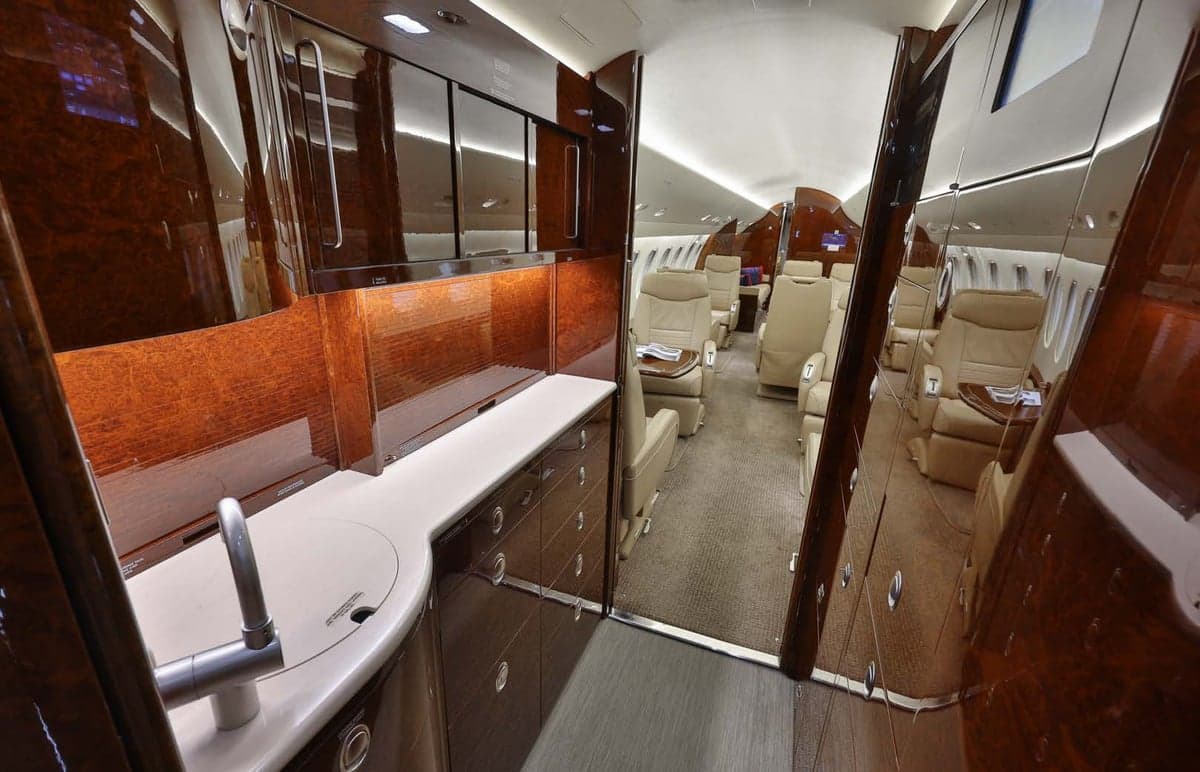 View of the aircraft interior showing a sink and cabinets, leading to the seating area.