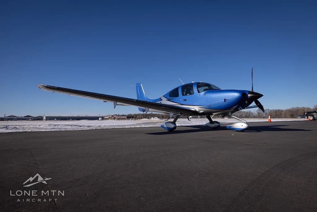 A low-angle front view of the blue and silver Cirrus SR22 aircraft (N627SG) on an airfield.