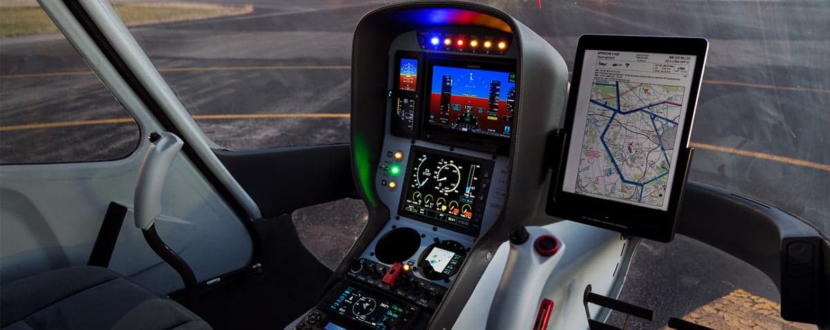 Helicopter cockpit with a digital instrument panel and tablet displaying a map.