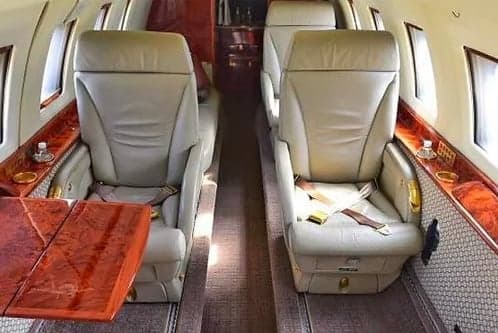 A view of the aircraft's interior with leather seats and a wooden table.