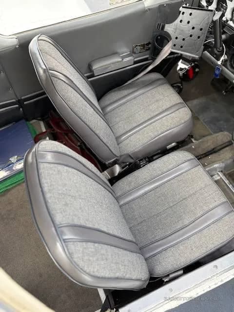 The gray fabric and vinyl front seats of an aircraft cabin.