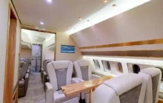 A view of the aircraft's interior, featuring leather seats and a wooden table.