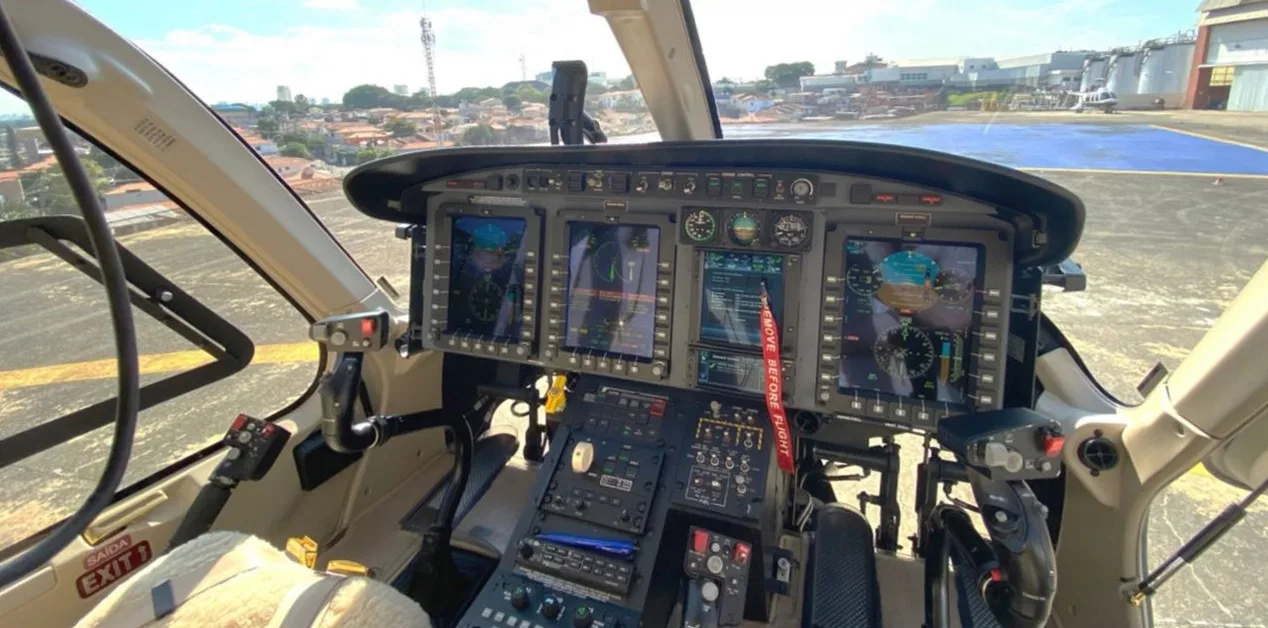 The modern glass cockpit of a helicopter, featuring multiple digital displays and control panels.