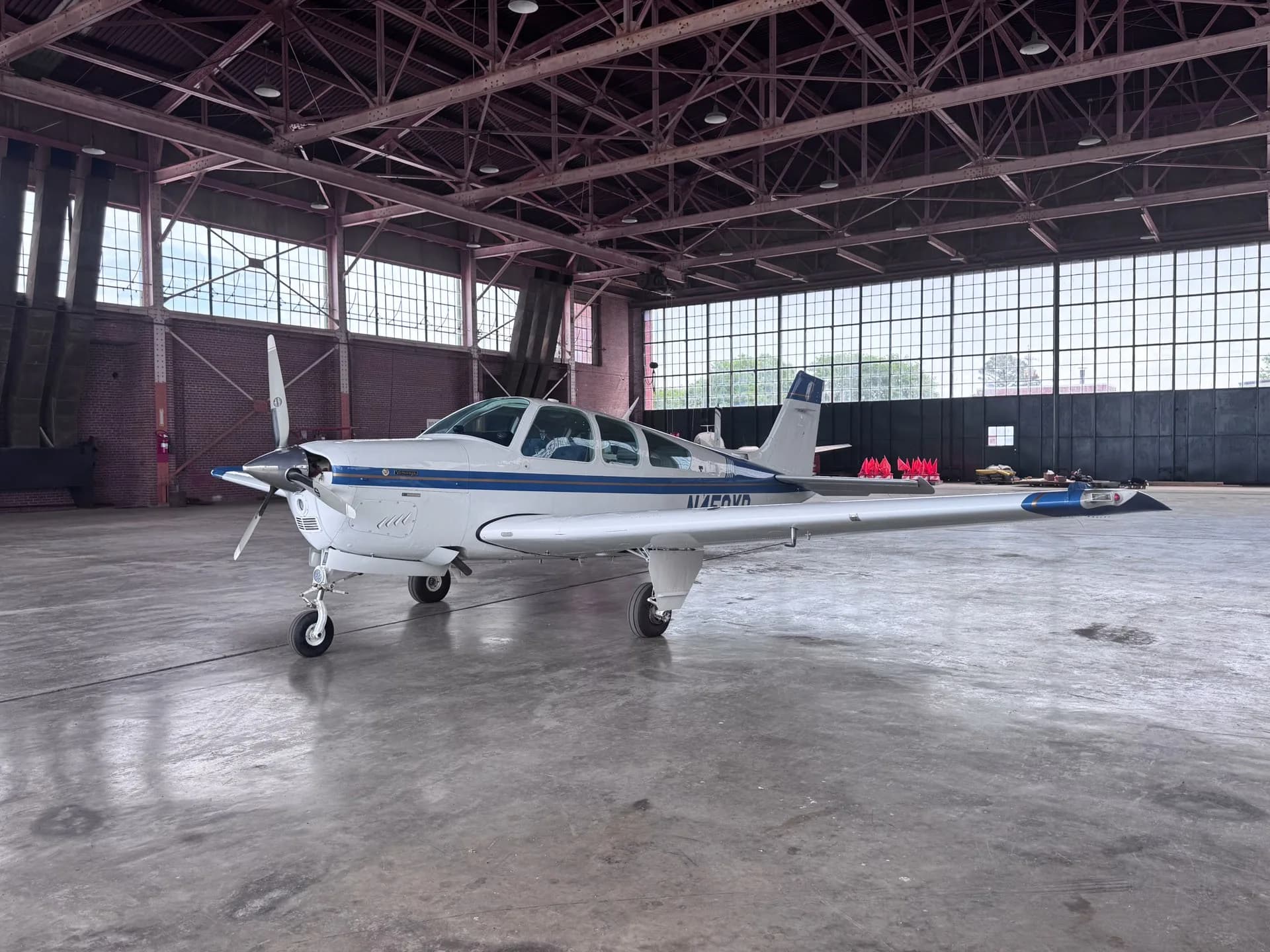 A white and blue single-engine aircraft with registration N450YR parked in a large hangar.