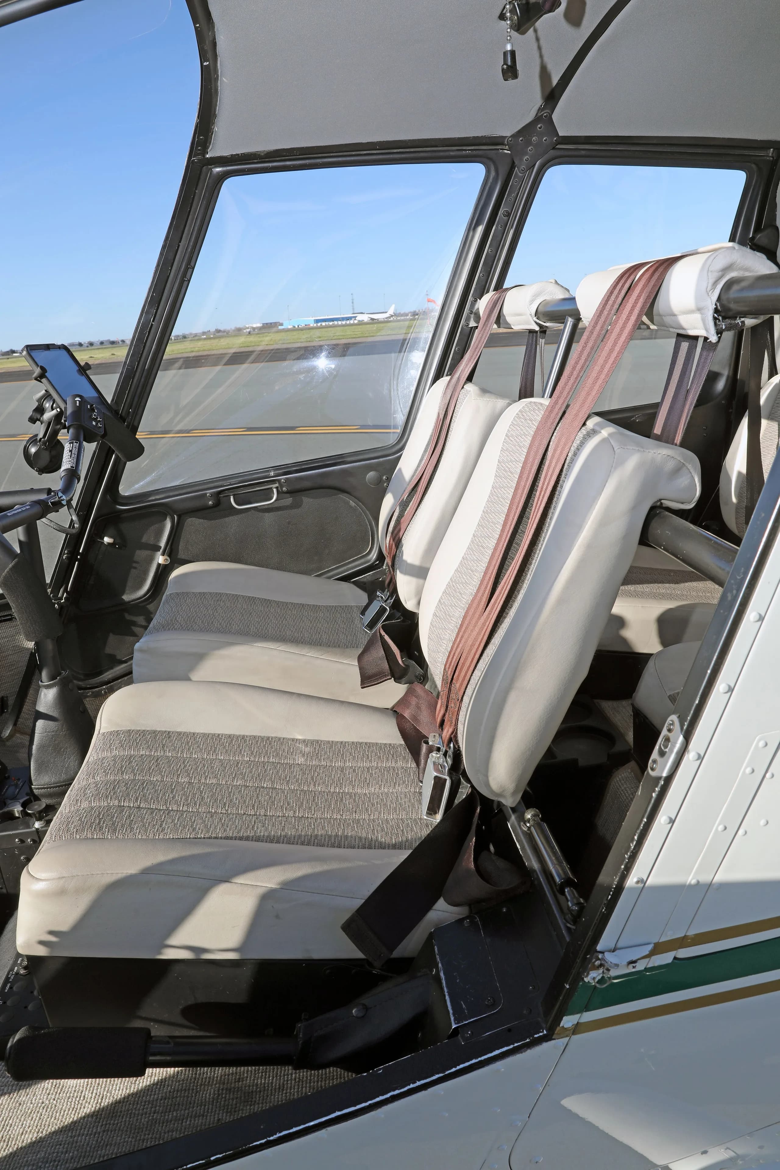 Interior view of the Robinson R44 Raven II helicopter cabin showing the front and rear beige seats.