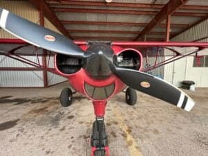 Front view of a red Cubcrafters aircraft with a black propeller.