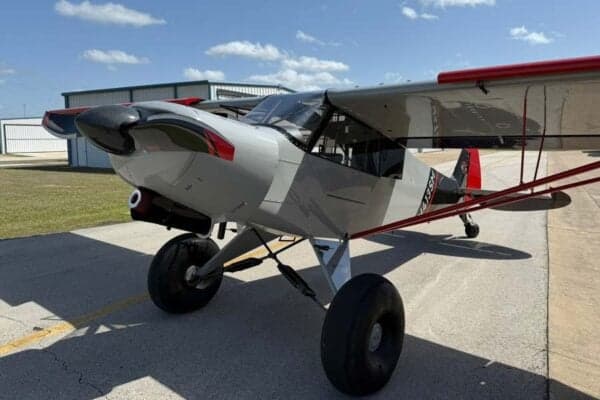 A gray and red N413SM aircraft is parked on the tarmac on a sunny day.