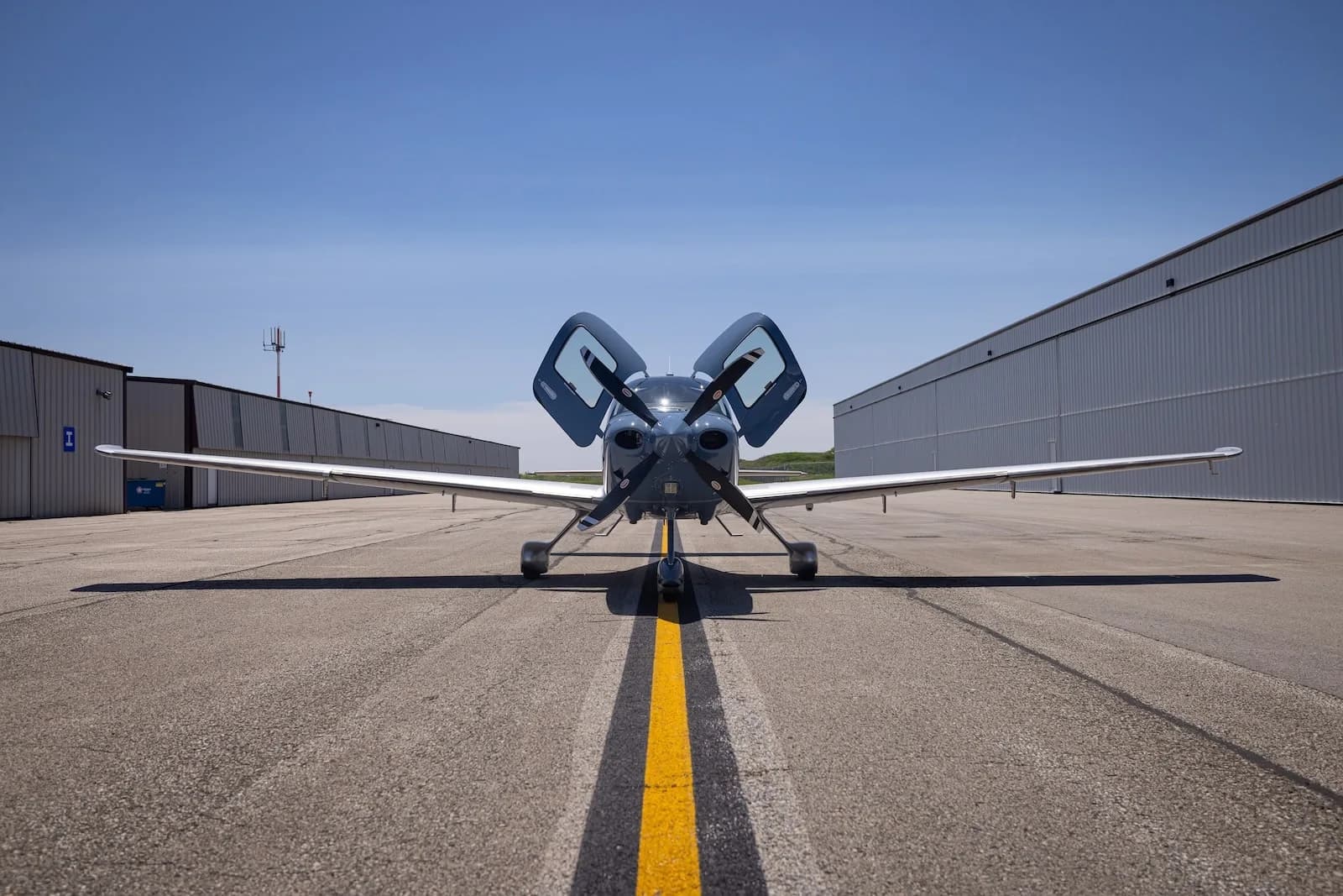 Front view of a Cirrus SR22T aircraft with open doors parked on the tarmac.