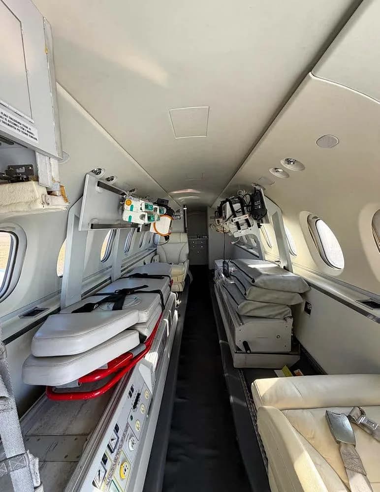 A view down the aisle of an air ambulance interior, equipped with medical stretchers and equipment.