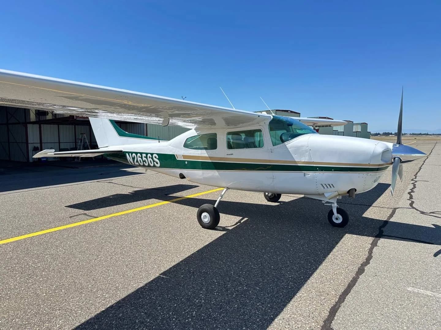 A white and green Cessna Centurion N2656S parked on an airfield, viewed from the front right.