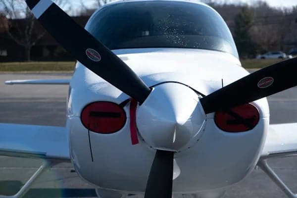 Close up of the propeller and nose of a white Cirrus aircraft.