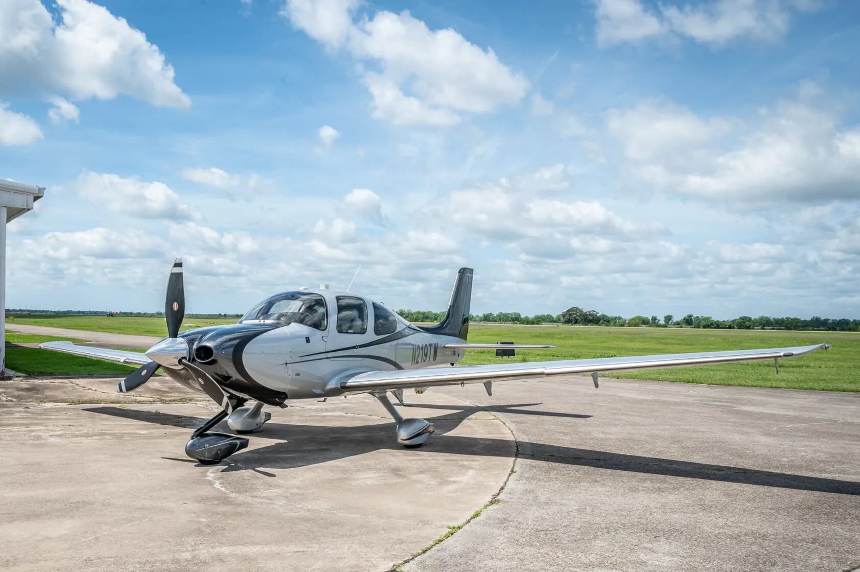 A front-side view of the silver and black Cirrus SR22T GTS Platinum aircraft N219TW on an airfield.