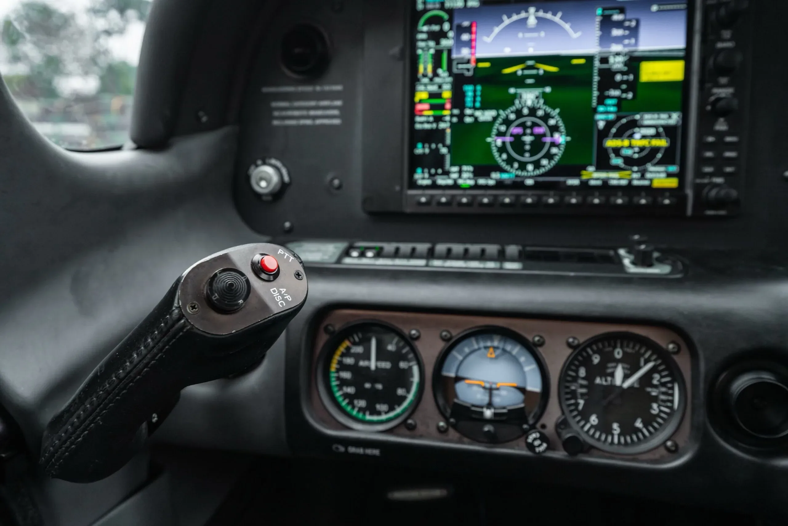 A close-up view of the aircraft's cockpit showing the primary flight display, analog gauges, and a control stick.
