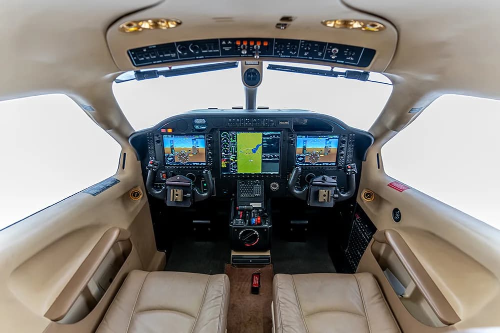 A wide view of the aircraft cockpit with multiple digital displays and controls.