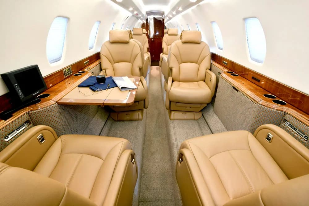 Aircraft interior with tan leather seats and wood trim.