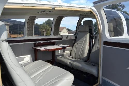 The interior of an aircraft cabin with gray leather seats and a small table.