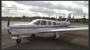 A Piper Saratoga aircraft with white and red stripes parked on the tarmac.