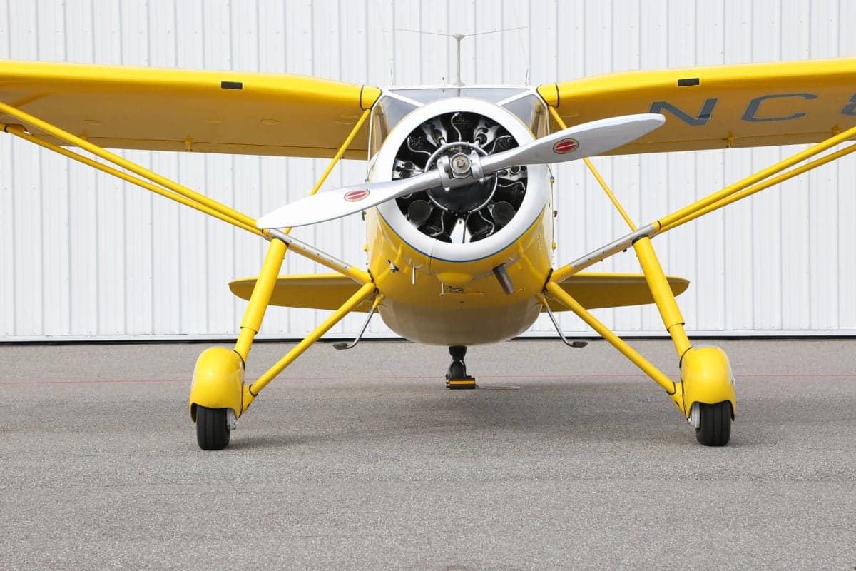 Close up front view of a yellow and white Stinson Reliant parked on the tarmac.
