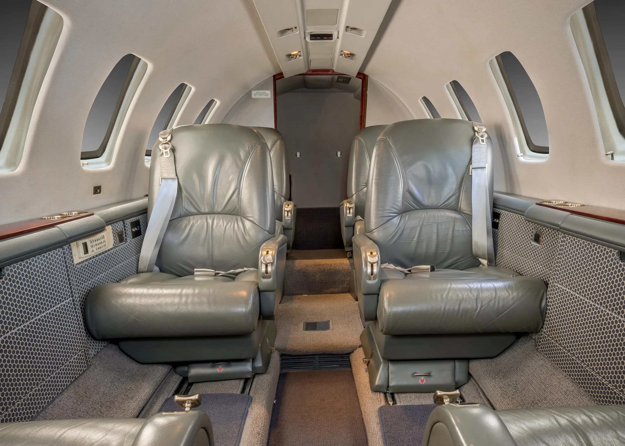 The aircraft cabin interior looking forward, showing two rows of grey leather passenger seats.