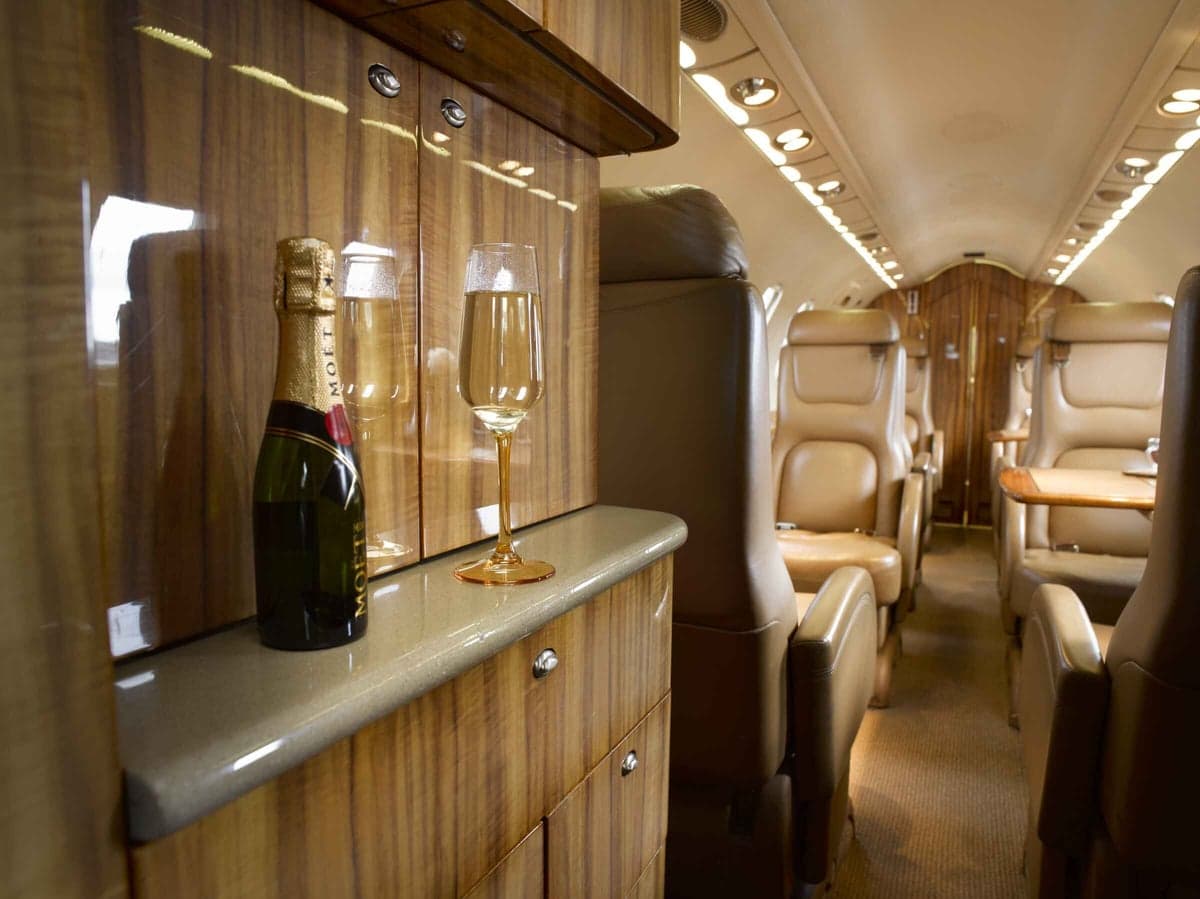 Interior view of the aircraft cabin with a bottle of champagne and a glass.