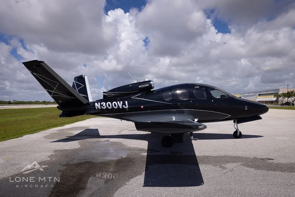 A black Cirrus Vision Jet (N300VJ) with silver accents parked on an airport tarmac, viewed from the side-right.