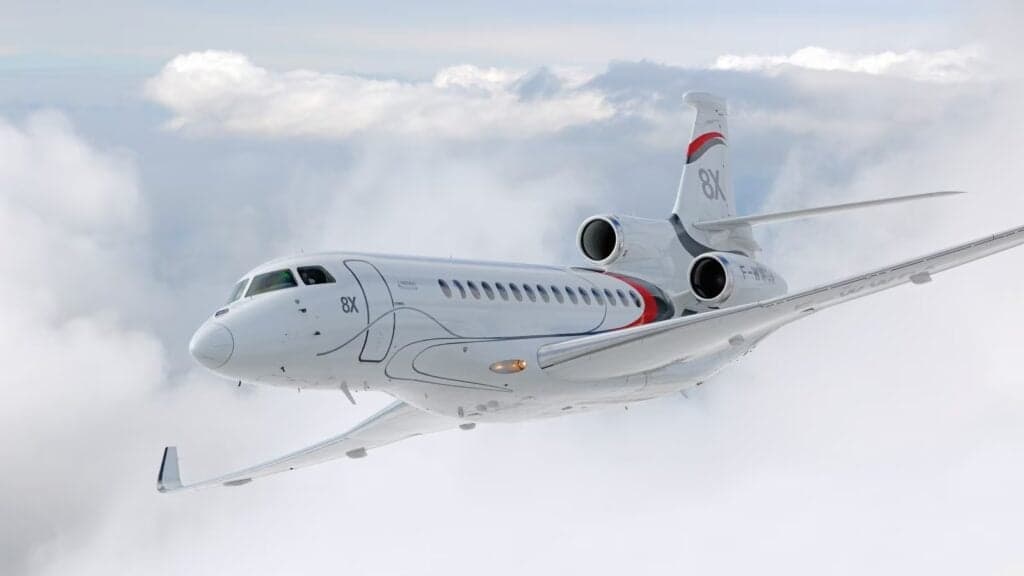 A Dassault Falcon 8X in flight against a cloudy sky.