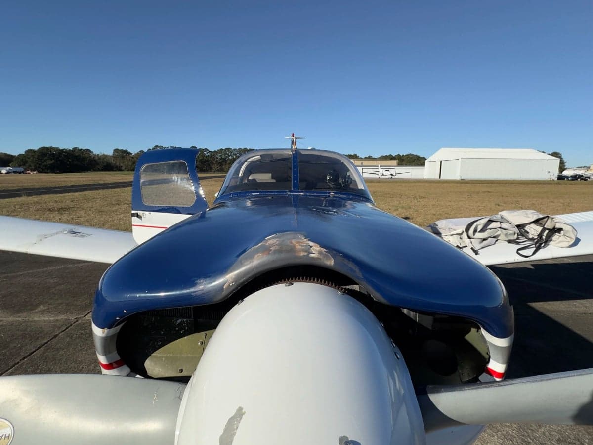 Close-up of the front of a blue and white Piper Cherokee aircraft.