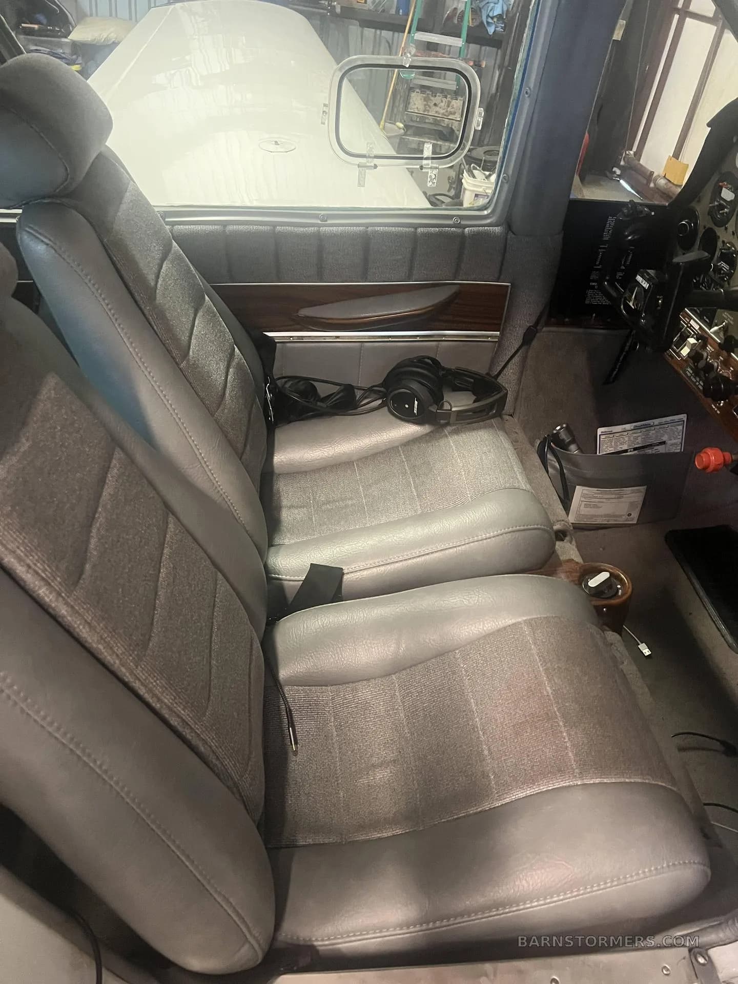 The gray and fabric front seats of an aircraft interior, with headphones on the seat.