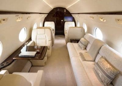 Aircraft interior featuring cream-colored seats and a sofa.