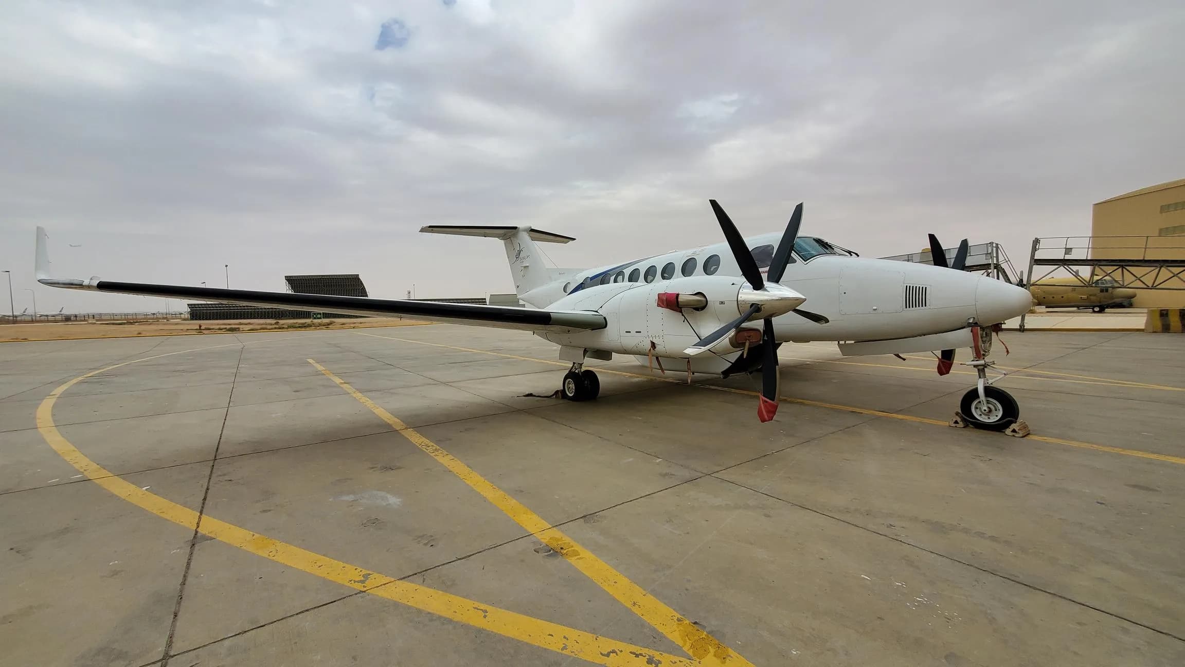 A King Air aircraft is parked on the tarmac on a cloudy day.