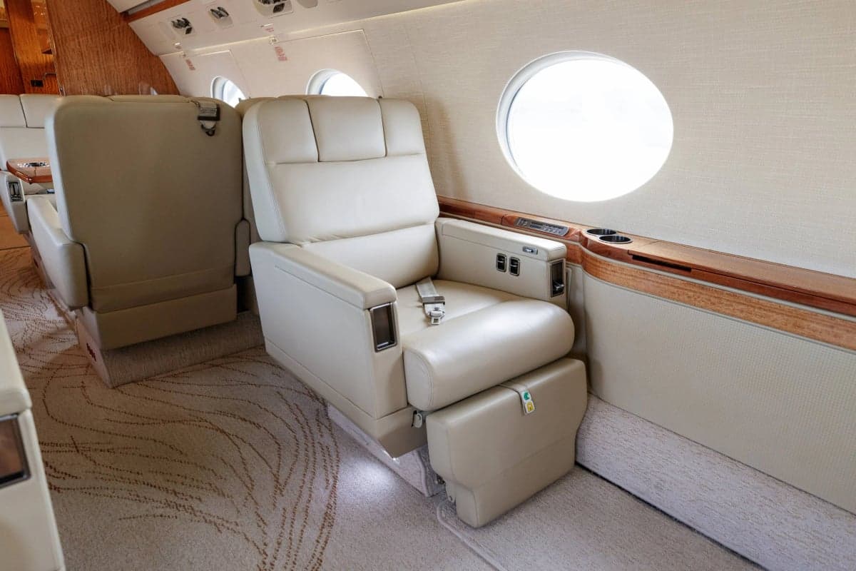 A close-up of a single seat in the Gulfstream G550 cabin, showcasing the leather upholstery and features.